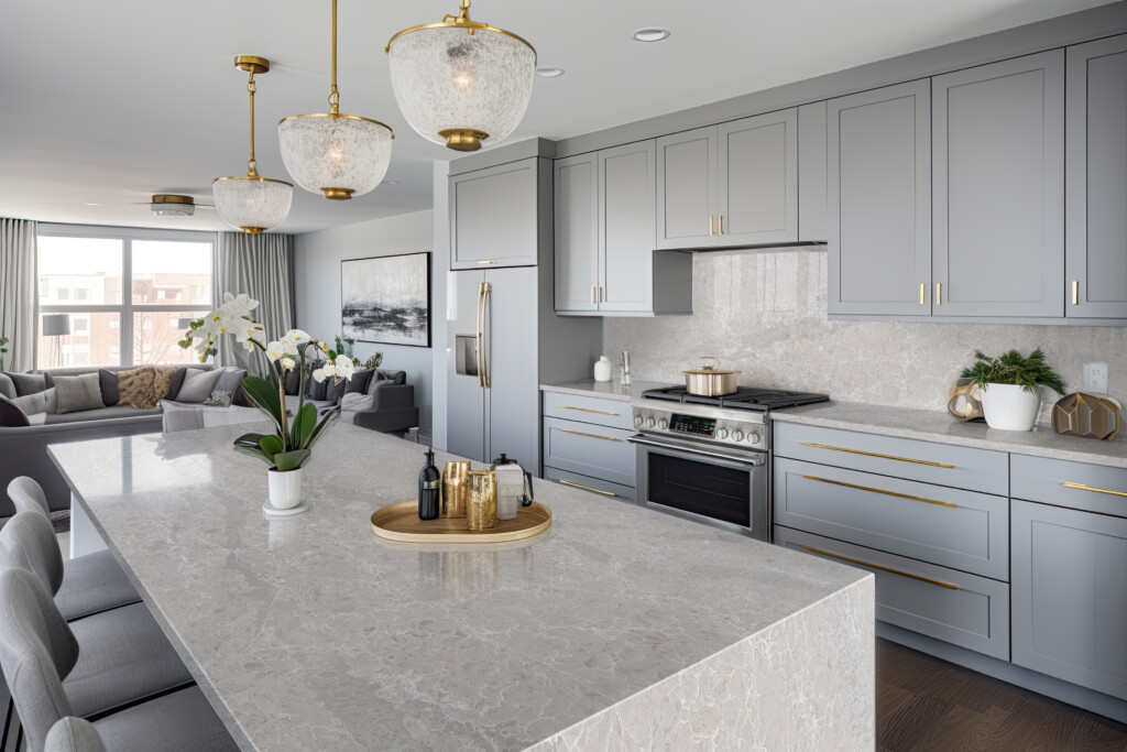 A stylish kitchen in Chicago with gold hardware, stainless steel appliances, and white marbled granite counters.